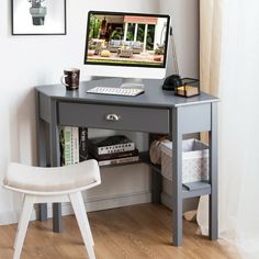 a computer monitor sitting on top of a desk next to a white chair and window