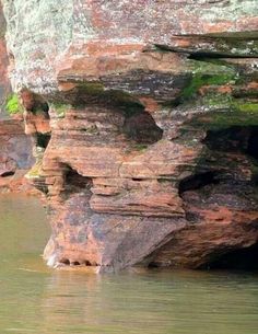 a rock formation in the water with moss growing on it