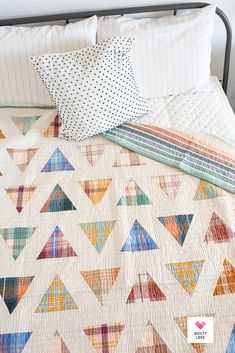 a bed topped with a colorful quilt and pillows next to a pillow on top of it