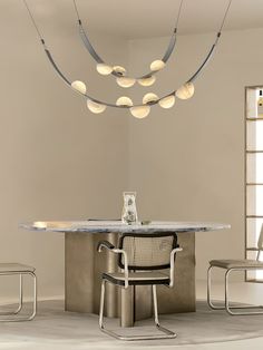 a modern dining table and chairs in an empty room with round lights hanging from the ceiling