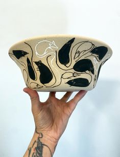 a hand holding up a black and white bowl