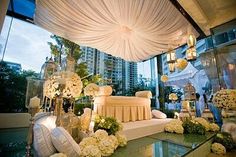 a room filled with lots of white flowers and decor on top of glass tables in front of large windows