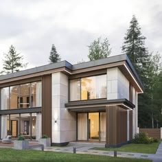 a modern house in the middle of a grassy area with trees and grass around it