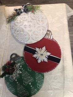 three christmas ornaments are sitting on top of a table with white doily and ribbon