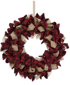 a red and white wreath with burlocks hanging from the side on a wooden stick