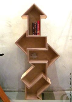 a wooden shelf with books on it and an arrow shaped book case in the middle