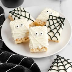 halloween treats are decorated with white icing and black spider webs on a plate