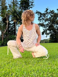 a man sitting in the grass with his hands on his knees and eyes wide open