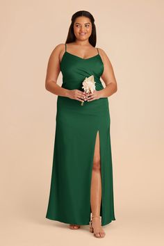 a woman in a long green dress with her legs slited up and holding a flower