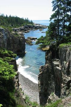 an ocean view with rocks and trees on the shore