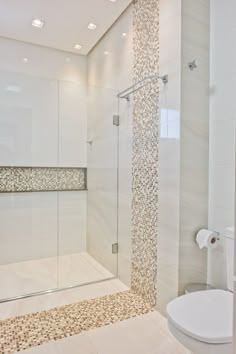 a bathroom with a glass shower door and tiled flooring, along with a white toilet