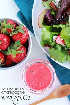 a bowl of strawberries next to a plate of salad