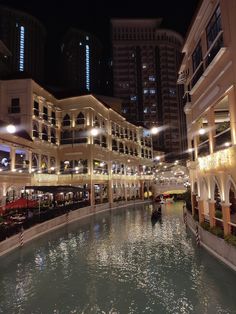 an indoor shopping mall at night with water in the foreground and buildings lit up