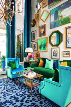 a living room filled with blue and green furniture next to a wall covered in pictures