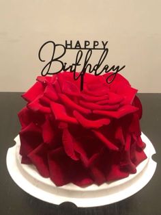 a birthday cake that has been decorated with red rose petals and the words happy birthday on it