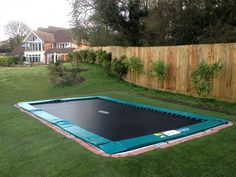 an inflatable trampoline is on the grass next to a wooden fence