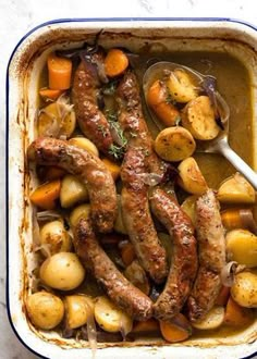 sausages, potatoes and carrots in a casserole dish with a spoon