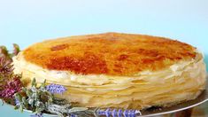 a stack of pancakes sitting on top of a metal plate next to purple flowers and leaves