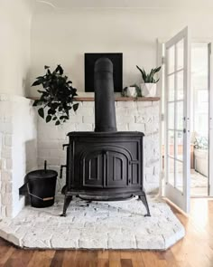 a black stove sitting in the middle of a living room next to a potted plant