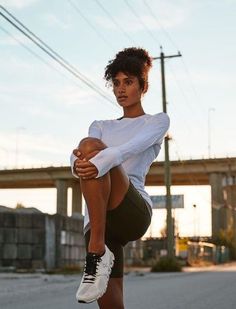 a woman in white shirt and black shorts doing a kickbox pose on skateboard