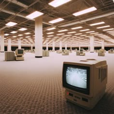 an old tv sitting in the middle of a large room filled with tables and chairs