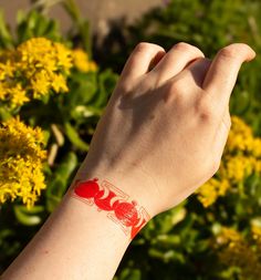 a person's arm with a red crab tattoo on it and yellow flowers in the background