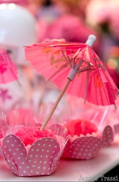 pink cupcakes and umbrellas are on the table