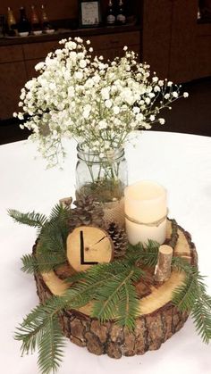 a vase with flowers and candles on top of a wooden slice that is sitting on a table