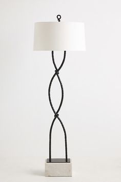 a lamp with a white shade on top of it and a black base in the middle