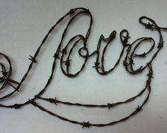 barbed wire with the word love spelled out in it's center, on top of a white surface