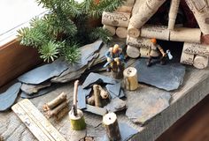 small figurines are sitting on top of wood logs and other items in front of a window