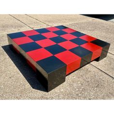 a coffee table made out of black, red and white squares on concrete ground with no one around it