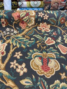 an upholstered fabric with colorful flowers and birds on it, in front of bookshelves