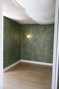 an empty room with green walls and white ceilinging is seen in this image from the doorway