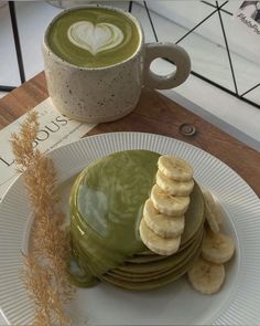 a stack of pancakes on a plate with green liquid and sliced bananas next to it