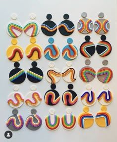 several pairs of colorful earrings are displayed on a white surface with black, yellow, red, blue, and green shapes