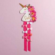 a pink unicorn head with flowers on it and name plaque attached to the back of it