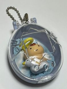 a small glass pendant with an angel on it's back hanging from a ball chain