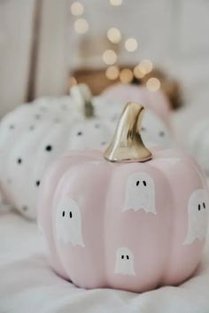 two pink pumpkins with ghost faces painted on them are sitting on a bed next to each other