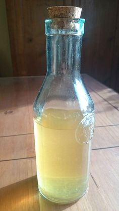 a glass bottle filled with liquid sitting on top of a wooden table