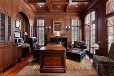 an office with wood paneling, leather chairs and a desk in front of a fireplace