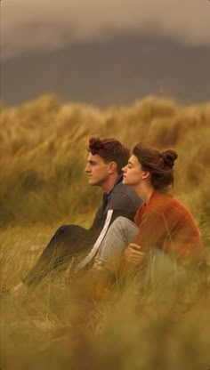 two people are sitting in the tall grass