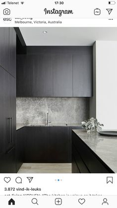 a modern kitchen with black cabinets and marble counter tops is featured in this image from the magazine