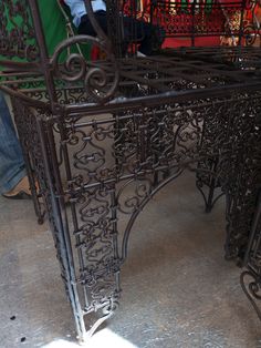 an ornate iron table is shown in the middle of a room with people standing around it