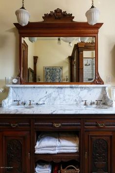 a bathroom vanity with marble counter top and wooden cabinetry, under a large mirror