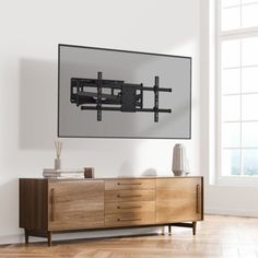 a large flat screen tv mounted to the side of a wooden cabinet in an empty room