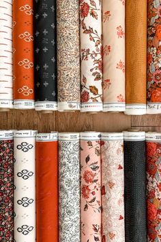 many different types of fabrics are lined up on the shelf in front of each other