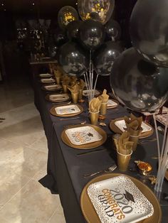 the table is set with black and gold party supplies, silver balloons, and confetti