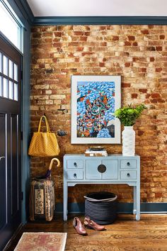 a room with brick walls and a painting on the wall next to a blue table