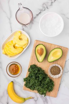 ingredients to make an avocado smoothie laid out on a marble counter top